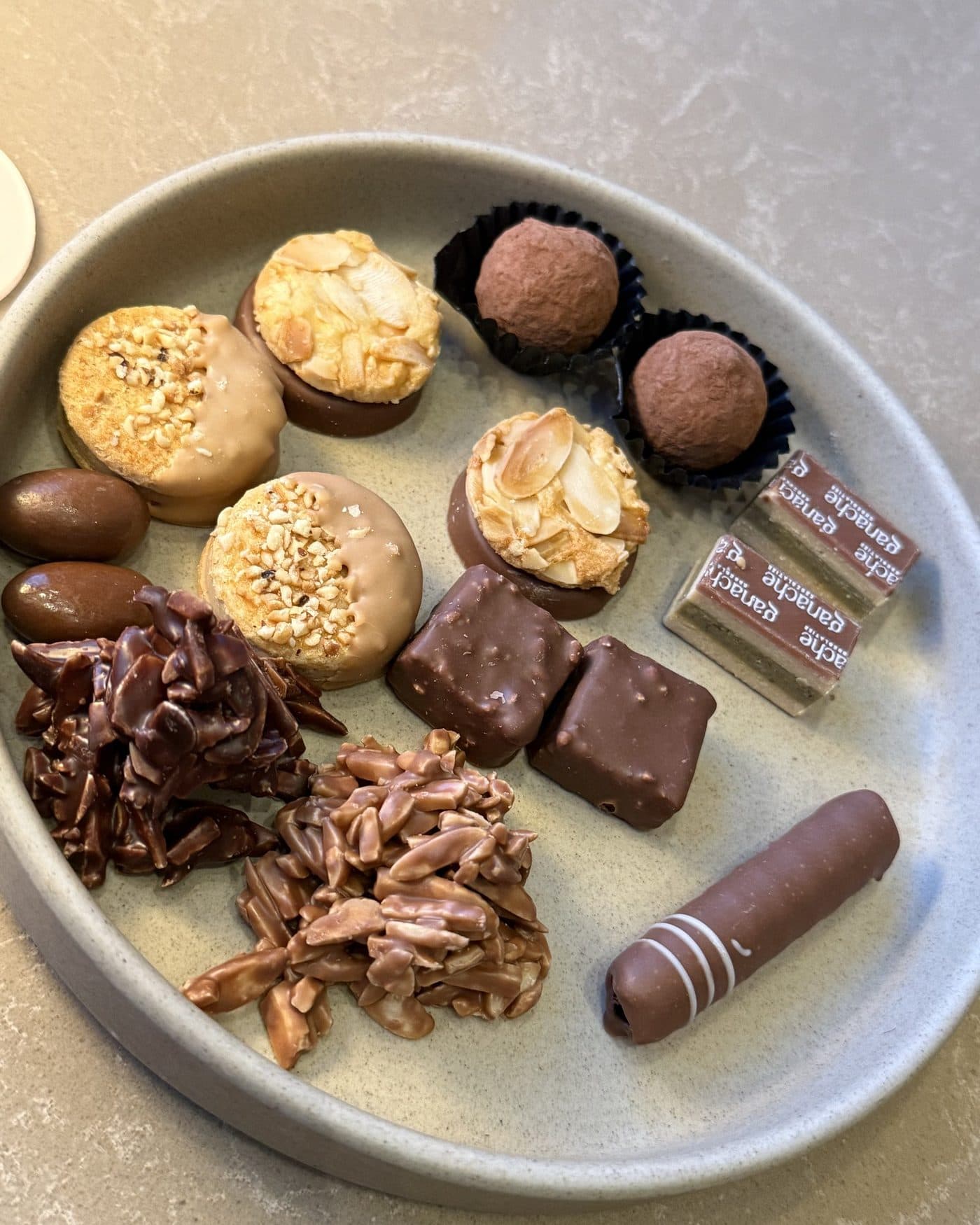Plate of pastries — almond bites, truffles, chocolate squares, and ganache rolls